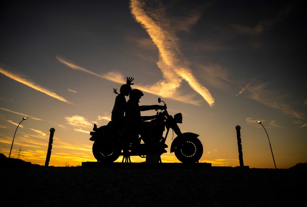 Dark silhouette of a motorcycle statue with the sunset in the background