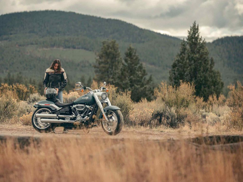 A person standing next to a Harley-Davidson bike.